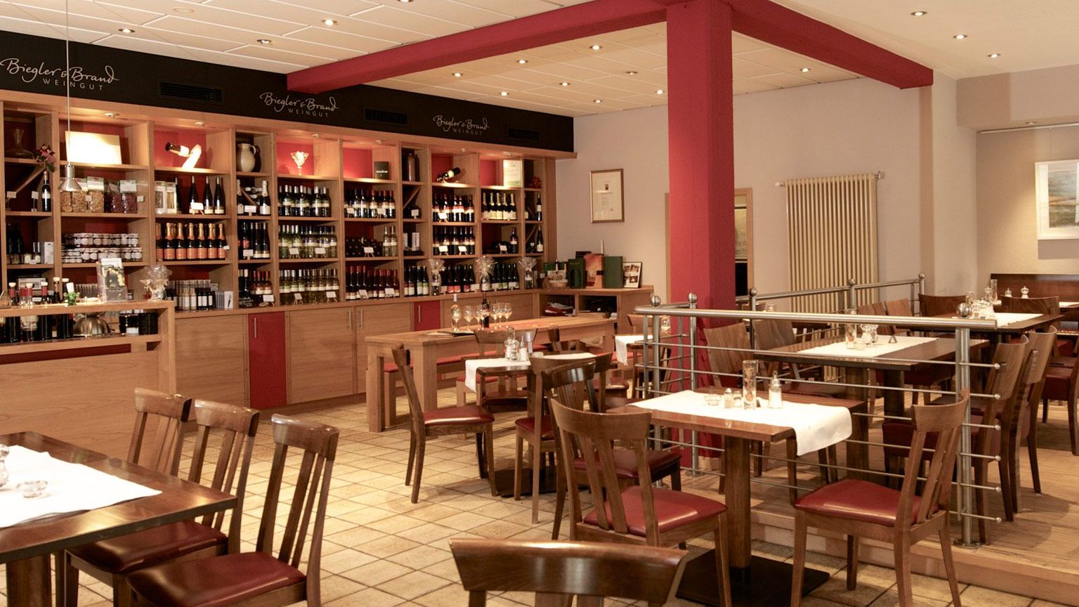 Weinrestaurant & Vinothek Kaisergarten - eingedeckte Tische und im Hintergrund ein Weinregal mit Weinen des Weinguts Biegler & Brand