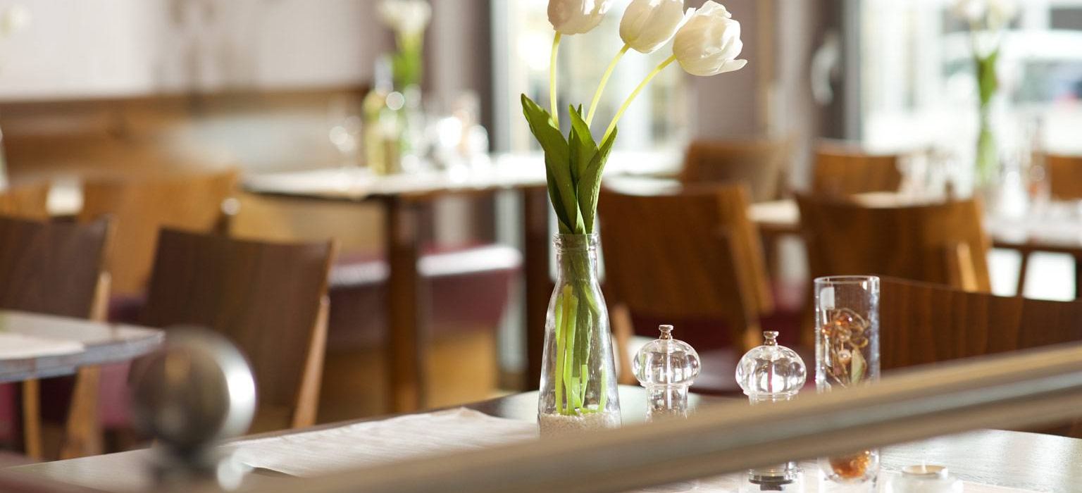 Blick auf Tische mit Blumenschmuck im Weinrestaurant & Vinothek Kaisergarten in Alzey